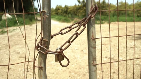Gate with rusty chain and lock next to country side road Video stock 107544499
