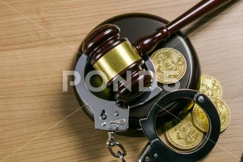 Gavel and handcuffs with bitcoins on wooden desk. Cryptocurrency legal concept. Stock Photos
