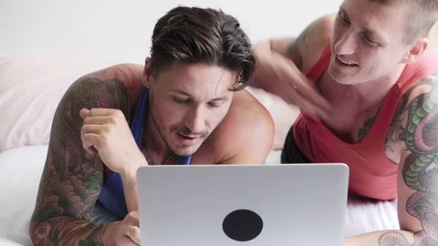 Gay couple in bed using laptop computer. Hugging. Stock Footage 105301859