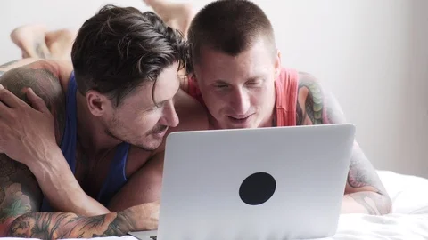 Gay couple in bed using laptop computer. Small sweet talk. Stock Footage 105301923