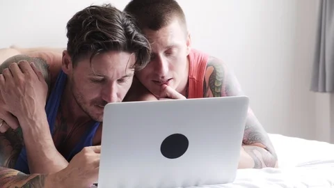 Gay couple in bed using laptop computer. Using keyboard. Stock Footage 105302014