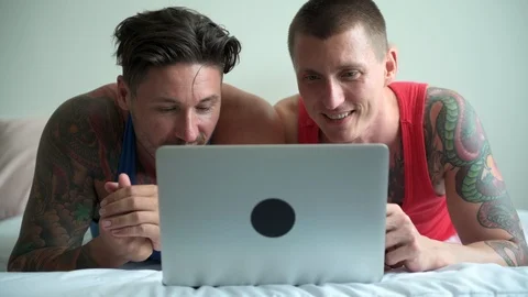Gay couple in bed using laptop computer. Laughing and smile. Stock Footage 105323022