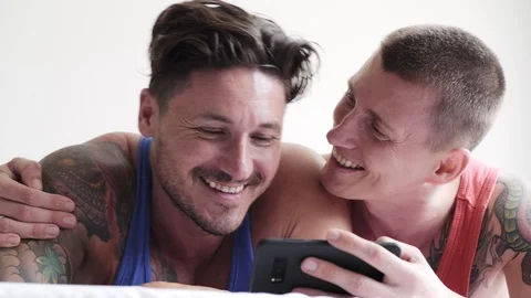 Gay couple in bed using phone. Video call their friends. Stock Footage 105301641