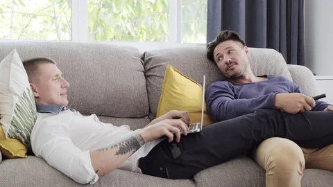 Gay couple relaxing on couch using laptop computer. Relaxing. Stock Footage 105297713