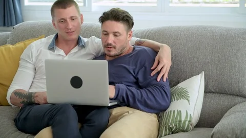 Gay couple relaxing on couch using laptop computer. Typing. Stock Footage 105314245