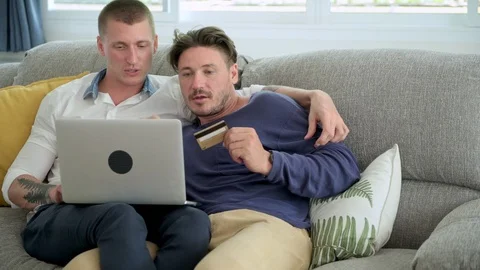 Gay couple relaxing on couch using laptop computer. Confuse mood. Stock Footage 105315332