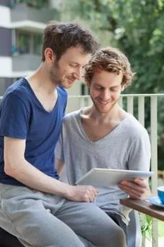 Gay couple using digital tablet at porch Fotos Stock