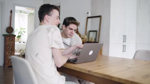 Gay couple using a laptop computer together at home Stock Footage 337883819