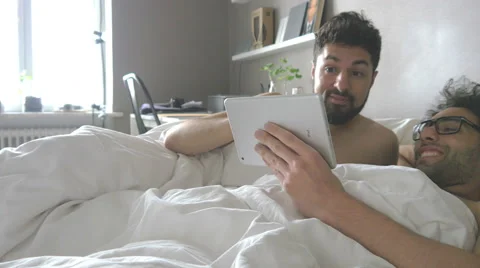 Gay couple using tablet in bed kissing Stock Footage 51332889