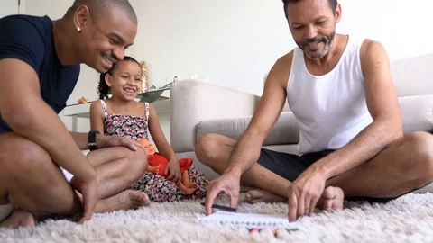 Gay Family with Adopted Child Drawing on Notebook at Home Stock Footage