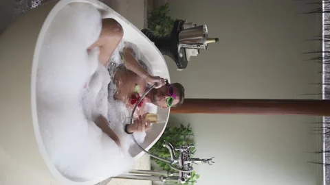 A gay guy is lying in a bubble bath with flower Stock Footage 146887771