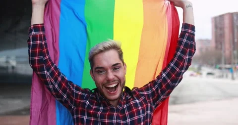 Gay man with makeup on having fun holding lgbt rainbow flag outdoor Vídeos de archivo 175792859