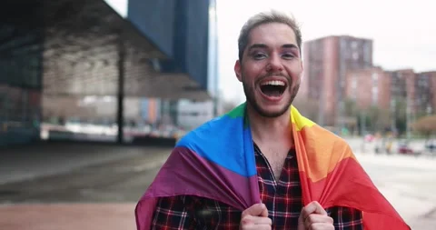 Gay man with makeup on having fun holding lgbt rainbow flag outdoor 動画素材 175792931