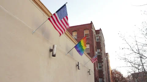 A gay pride flag flies between two US flags Stock Footage 46363606