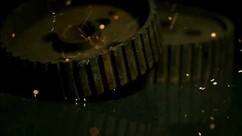 Gears on dark floor with falling and bouncing sparks Stock Footage 327514510