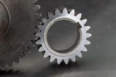Gears on a metal workshop table. Spare parts for industrial machines. Stock Photos