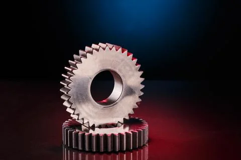 Gears rest on a reflective dark surface Foto stock
