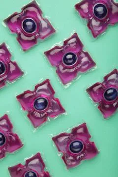 Gel capsules with laundry detergent on mint background. Vertical photo Stock Photos