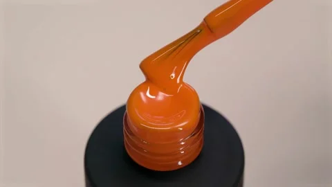 Gel polish orange thick texture. Varnish flows from a brush into a black tube Stock Footage 173190335