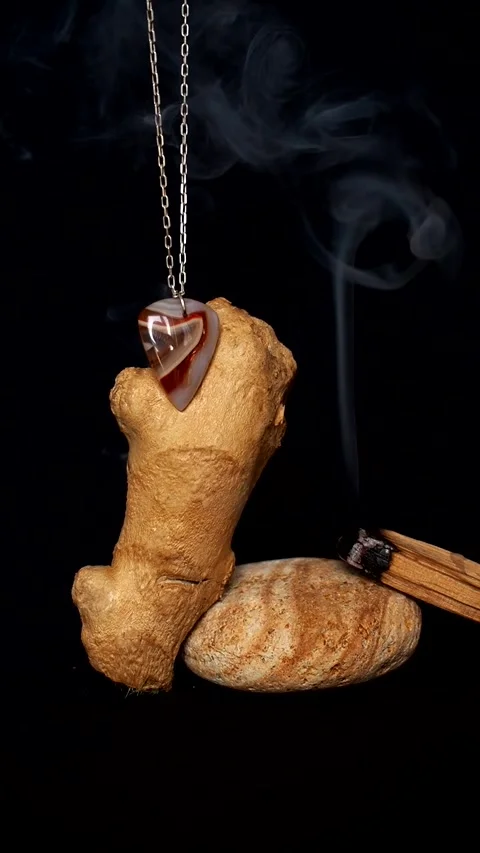 Gem stone on a silver chain next to ginger root and smoking palo santo Stock Footage 248529655
