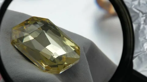 Gemologist jeweler evaluates the value and purity of yellow stones at a paw.. Stock Footage 332795320
