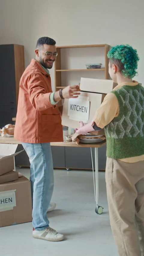 Gen Z Girl with Bionic Arm Handing Moving Boxes to Smiling Boyfriend in Kitchen Stock Footage 323304399