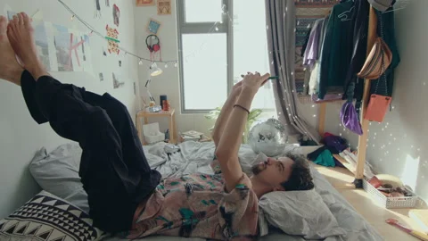 Gen Z Guy Taking Selfies on Bed in Room with Trendy DIY Decor Stock Footage 235660674