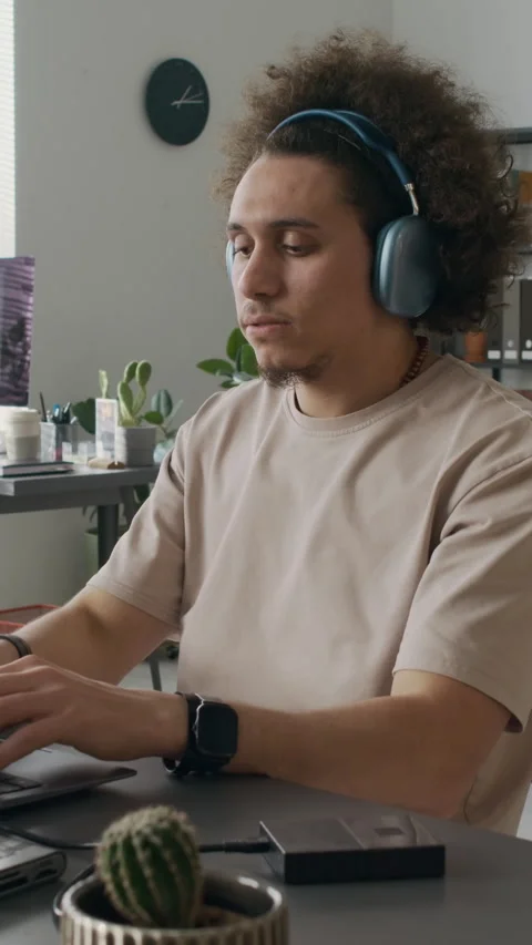 Gen Z Male Developer Putting on Headphones and Starting Coding on Laptop Stock Footage 299204210