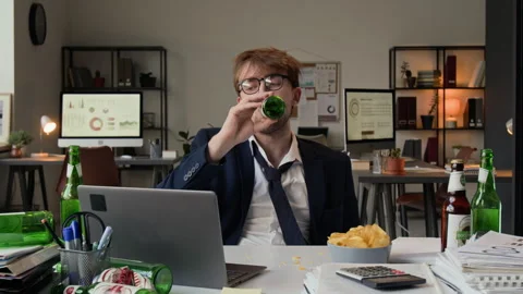 Gen Z Man Drinking Beer and Eating Chips Looking at Laptop Screen at Messy Desk Stock Footage 331532697