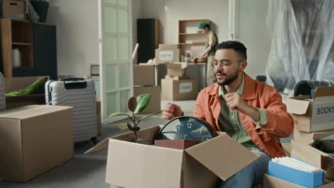 Gen Z Man Noticing Framed Picture in Box and Asking Girlfriend to Come to Him Stock Footage 323305529