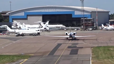 General Aviation Terminal Private Jets Overview with airplane back view taxiing Stock Footage 235010355
