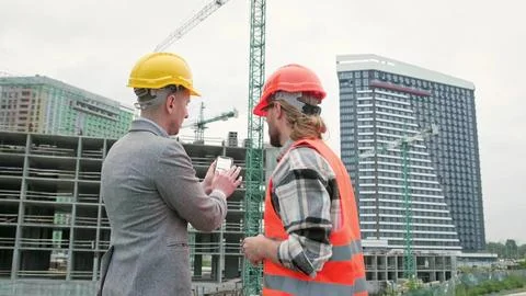 General contractor and subcontractor using smartphone during site inspection Stock Photos