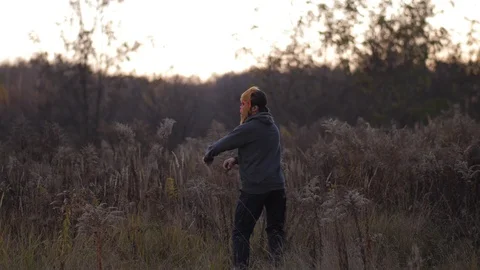 General plan. In the autumn field a guy dancing in a mask of a monkey 4K Slow Mo Stock-Footage 100067403