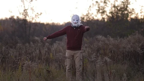 General plan. In the autumn field, a high guy in a bear mask dances 4K Slow Mo Stock-Footage 100067386