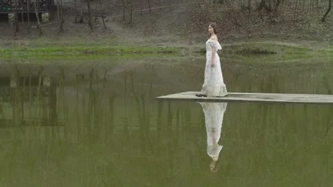 General plan is a girl on the lake with a reflection of herself in the water Vídeos de archivo 166530464