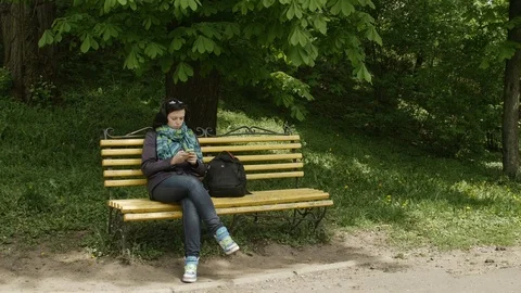 General plan of a park bench and the woman with glasses on her head sitting and Vidéo 103254353
