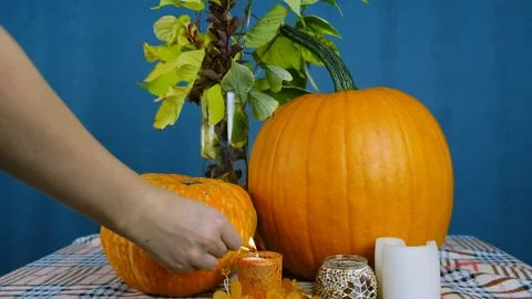 General plan of pumpkins and candles. The girl lights a candle. Stock Footage 210177188