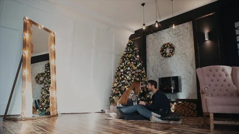 General plan view of a couple sitting opposite next to the Christmas tree and Stock-Footage 104132631