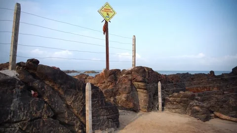 General plan of a wild beach with a sign of danger, on video pillars and stones. Video stock 243229729