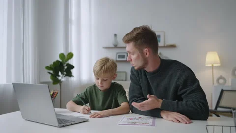 The general plan: A young dad helps his 7-year-old son to do homework sitting at Stock Footage 219545884