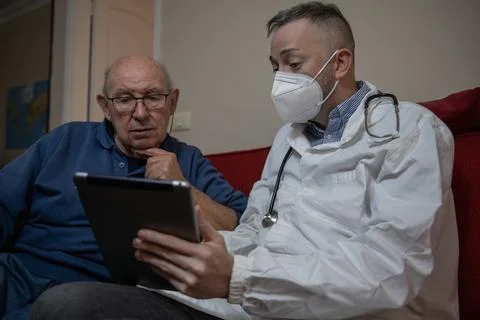 A general practitioner during a home visit to his elderly patient Stock Photos