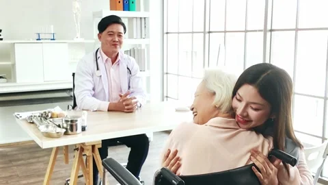 A general practitioner supports a smiling senior woman in a wheelchair. 動画素材 310542846