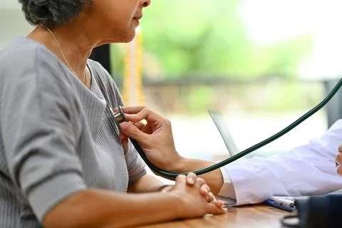 General practitioner using stethoscope checking heart and lungs of elderly Foto stock