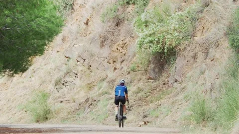 General shot of a cyclist going up the mountain with a gravel bike. Video stock 139617593