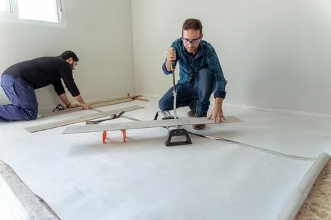 General shot of two men working on the installation of a laminate wood floor Stock Photos