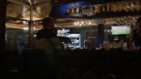 General View of a bar with a client sitting back and the barman cleaning his Stock-Footage 103337230