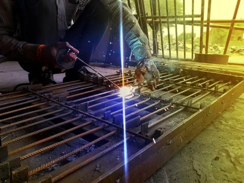 Generating blue sparks while worker welding on iron in industrial workshop Stock Photos