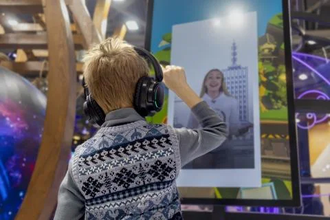 Generation Alpha boy wearing wireless headphones interacts with an interactiv Stock Photos