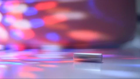 A generic AA size battery rolls into focus among flashing party lights. Stock Footage 111817242
