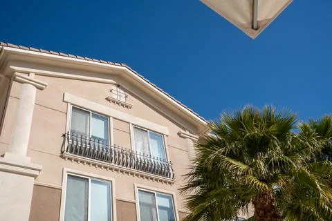 Generic facade of a resort with palm trees and blue sky with corner of poolside Stock Photos